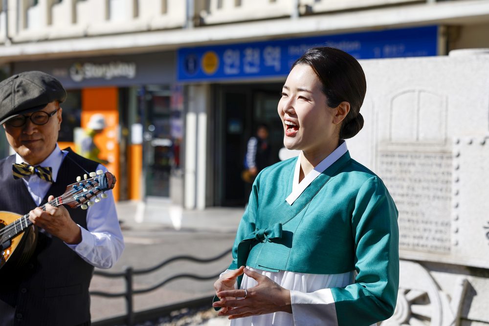 성악가와 만돌린 연주자가 인천역 앞에서 라이브 공연하는 모습
